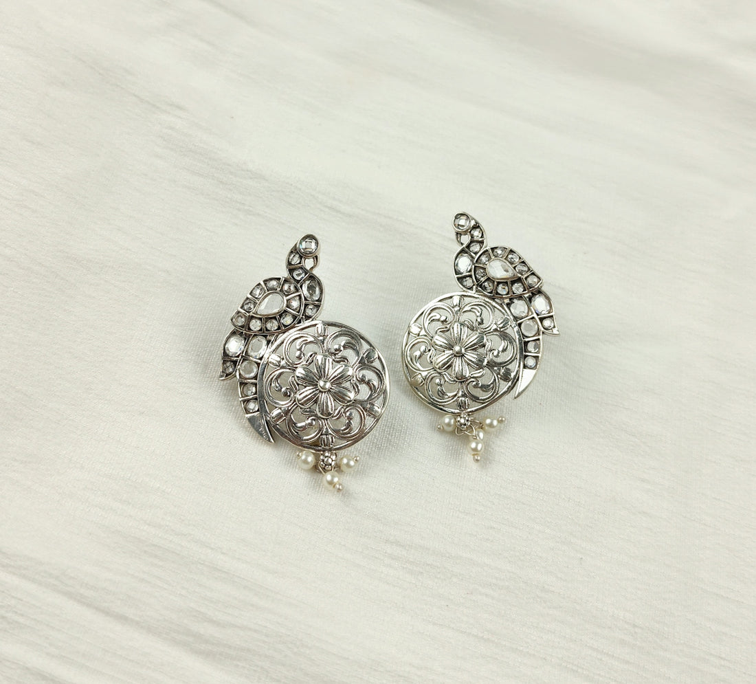 a pair of silver colored earrings on a white background